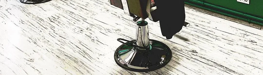 Bārddziņa krēsla hromēta pamatne uz gaišas koka grīdas pie zaļās sienas